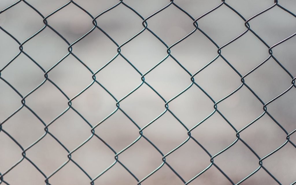 chain-linked-fence-683402 Detailed closeup of a metal chain-link fence with a blurred neutral background, perfect for textures and overlays.
